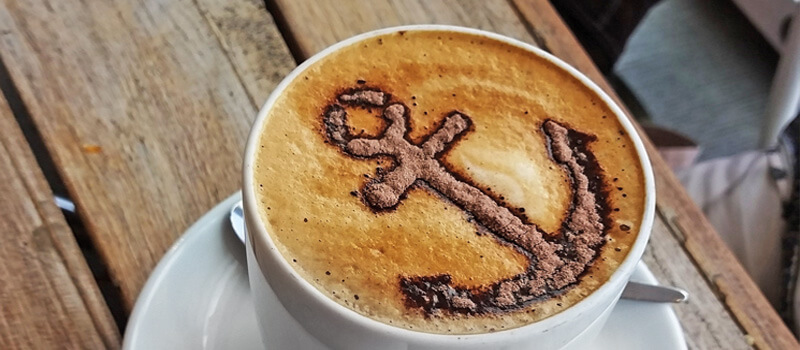 Tasse Kaffee mit Anker Symbol auf Milchschaum